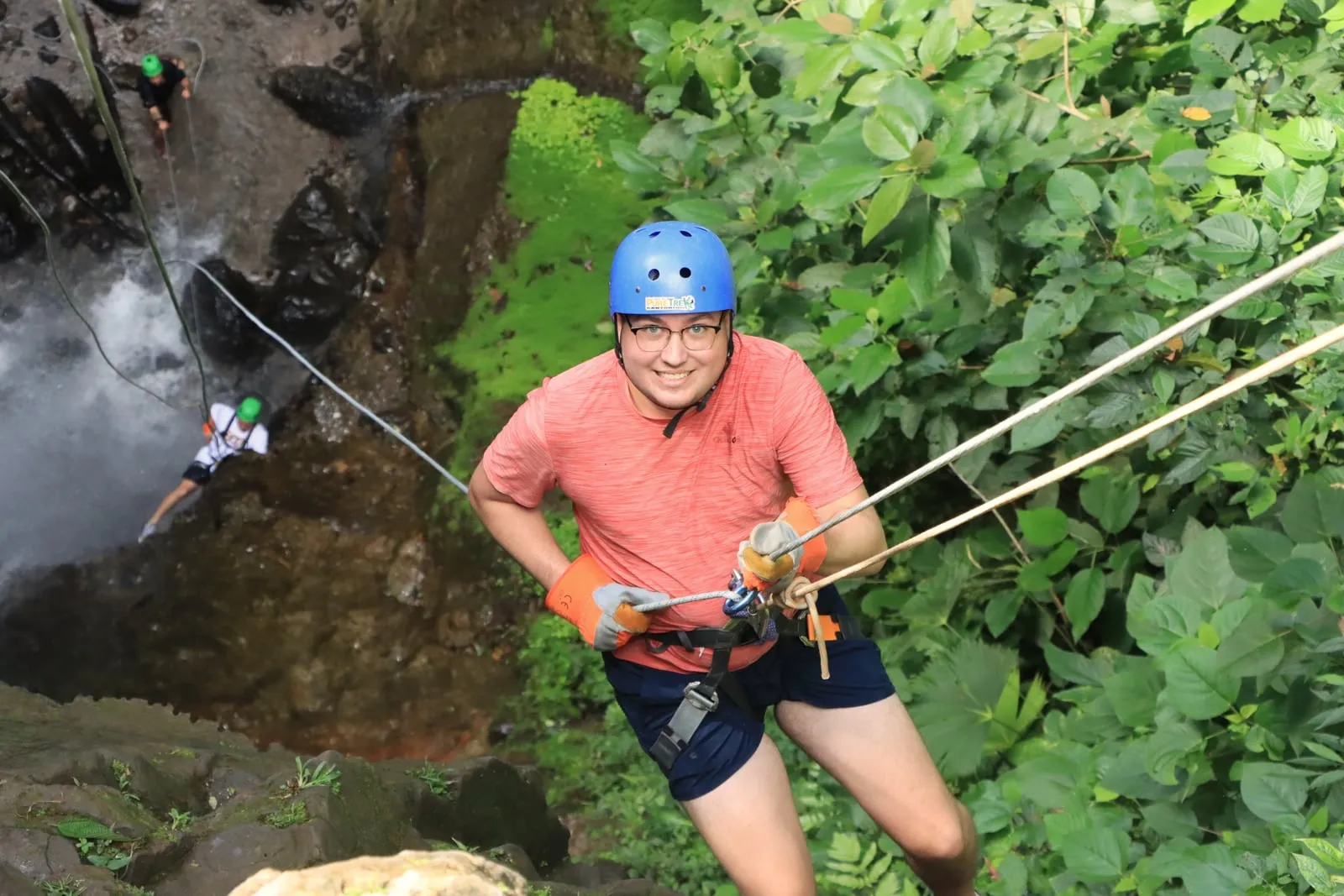 Dominic in climbing gear rappelling beside a waterfall in a Costa Rican canyon