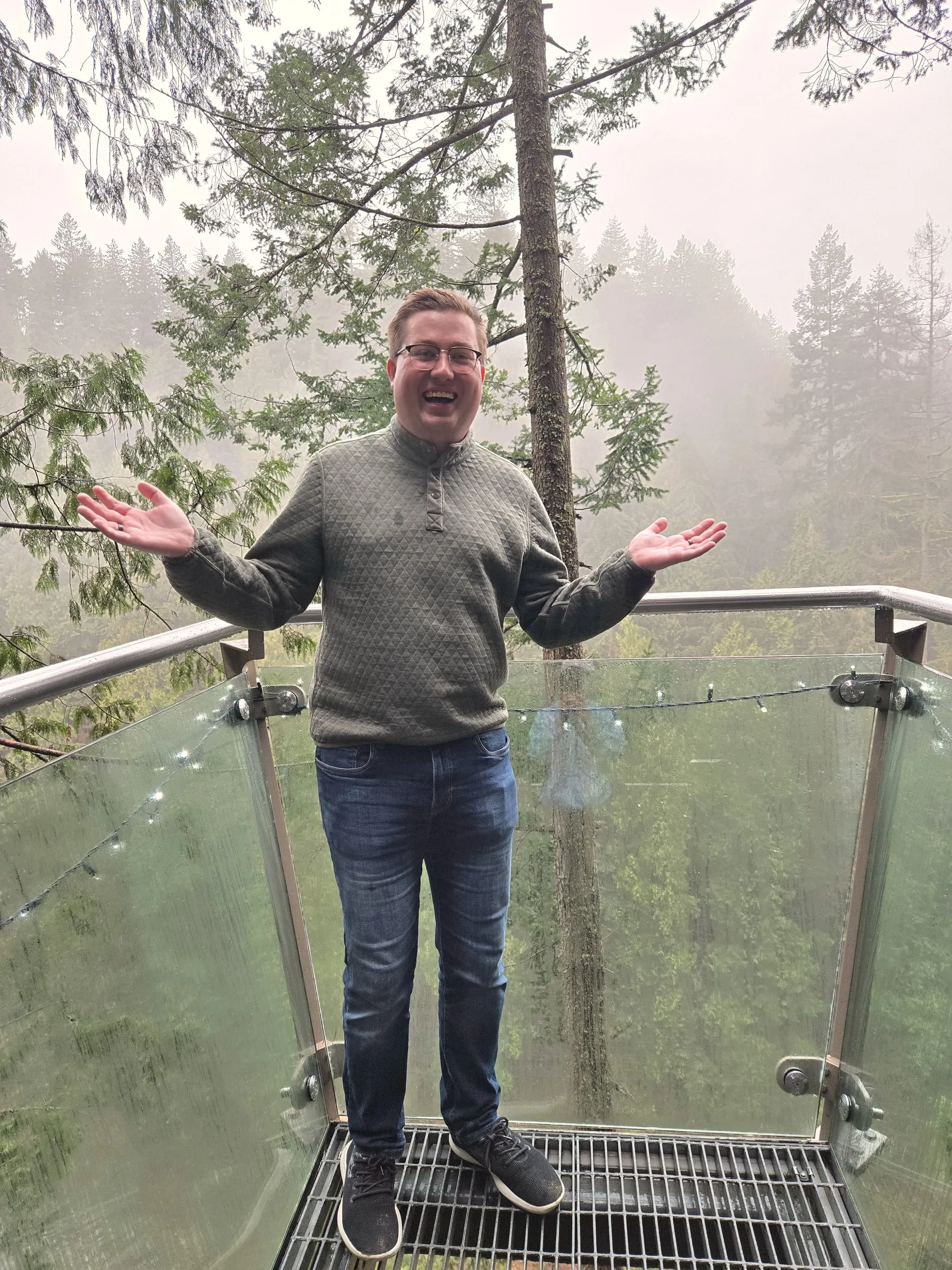 Dominic Hupp smiling on a glass-floored treetop walkway in a foggy forest